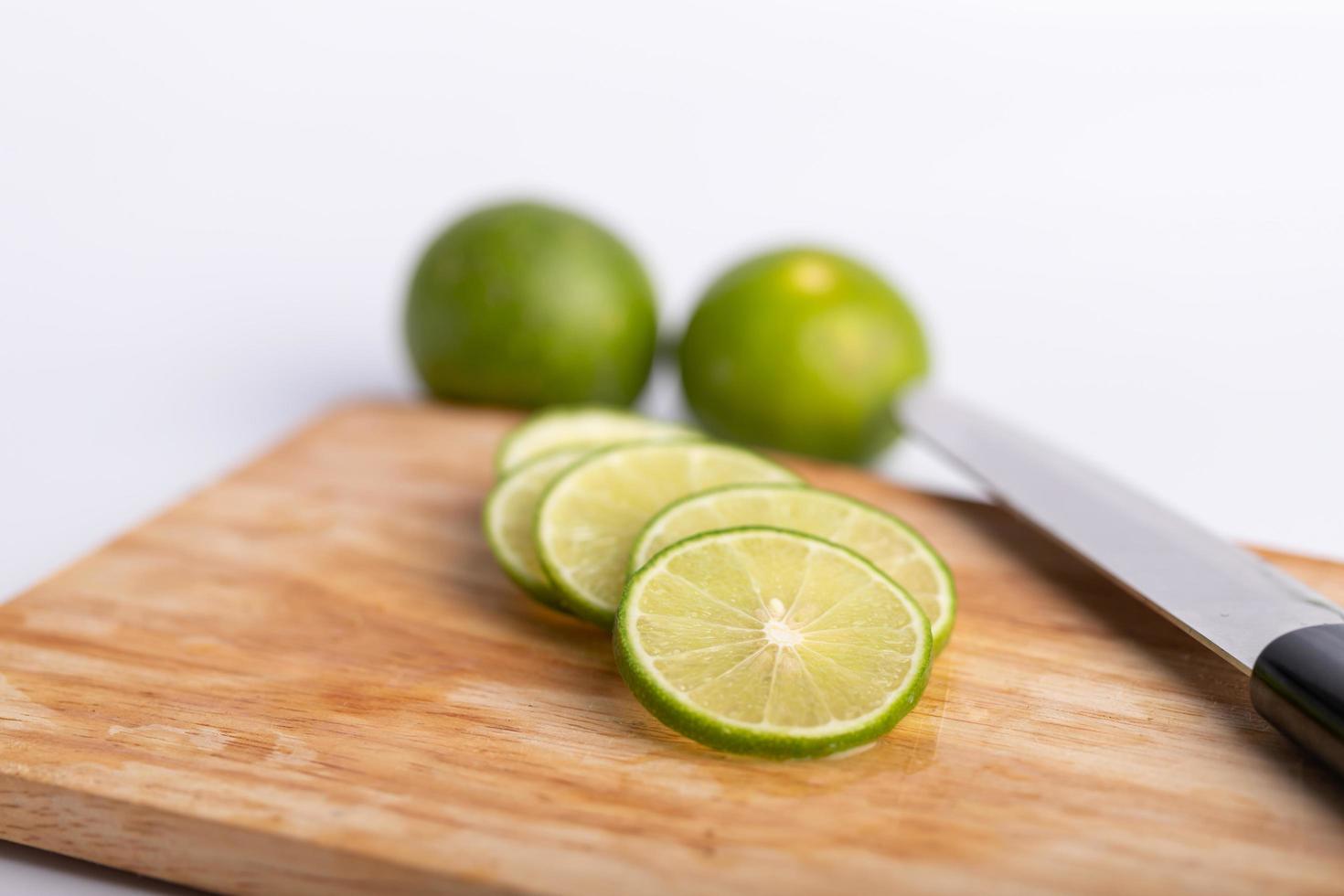 sliced of the green lime and seed with a knife place on wooden board photo