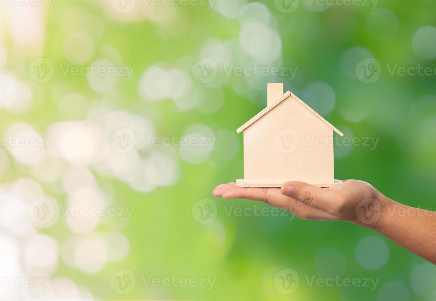 Small home model on the hand of women on green bokeh background photo