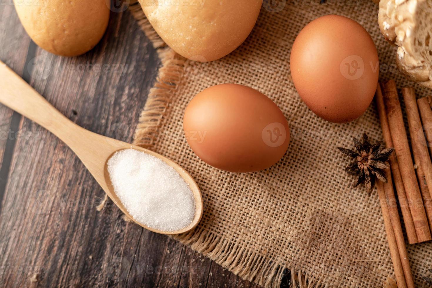 Flour in wooden spoon and eggs on the sack photo