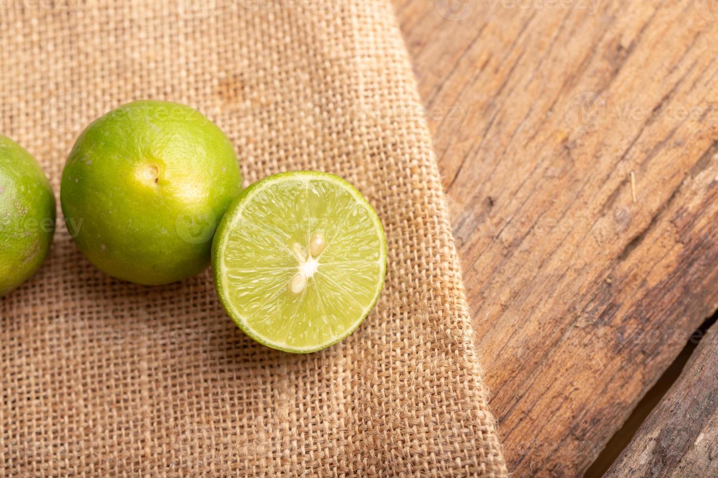 Close up a half of the green lime and seed place on woven sack on the wood table in a kitchen photo