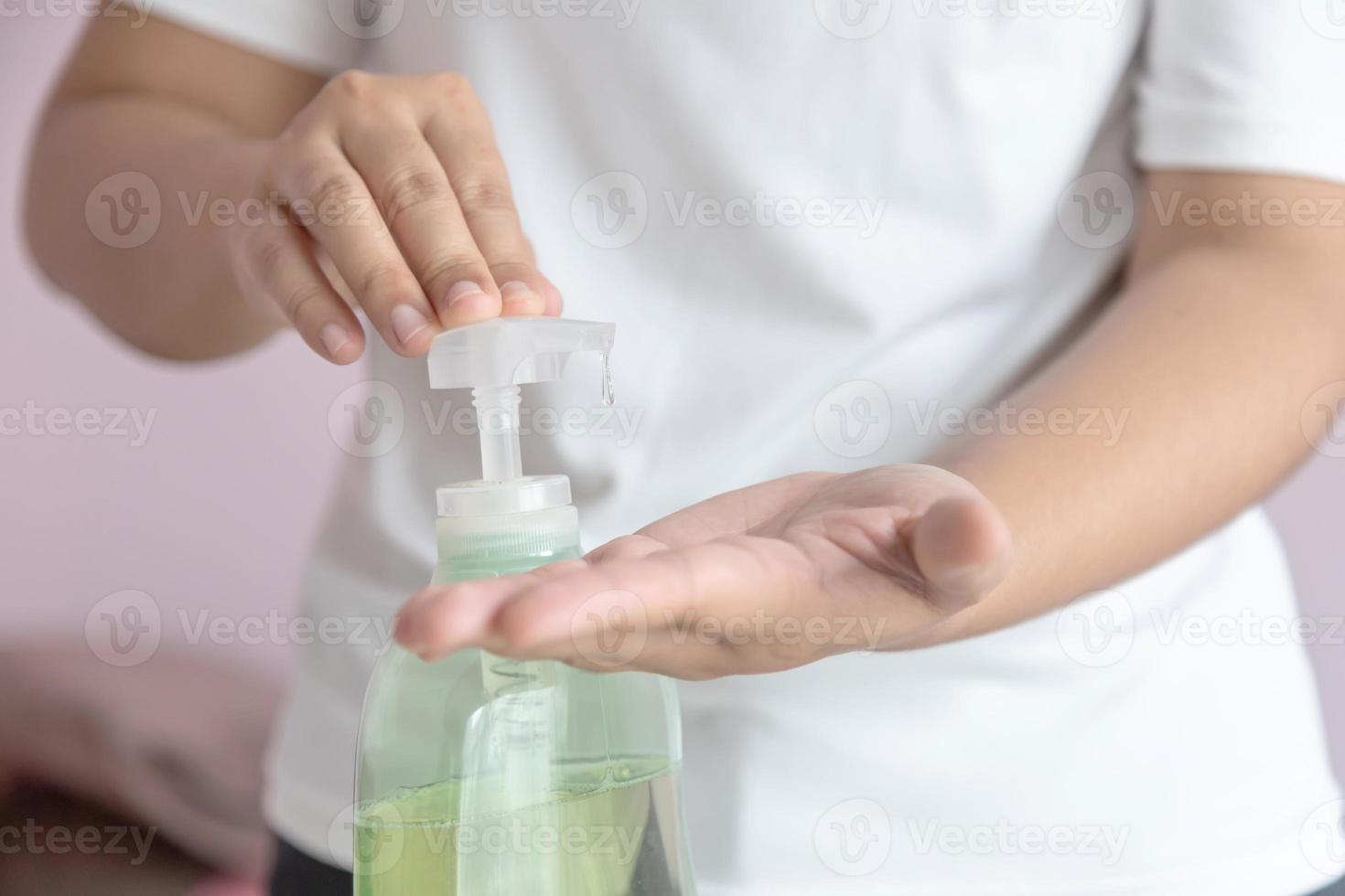 The woman squeezed the alcohol gel in a pump bottle into the palm to clean and kill germs. photo