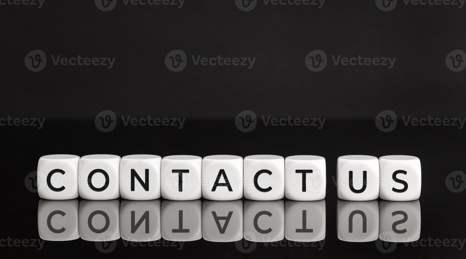 Contact us phrase on white blocks shape on black background. Copy space photo