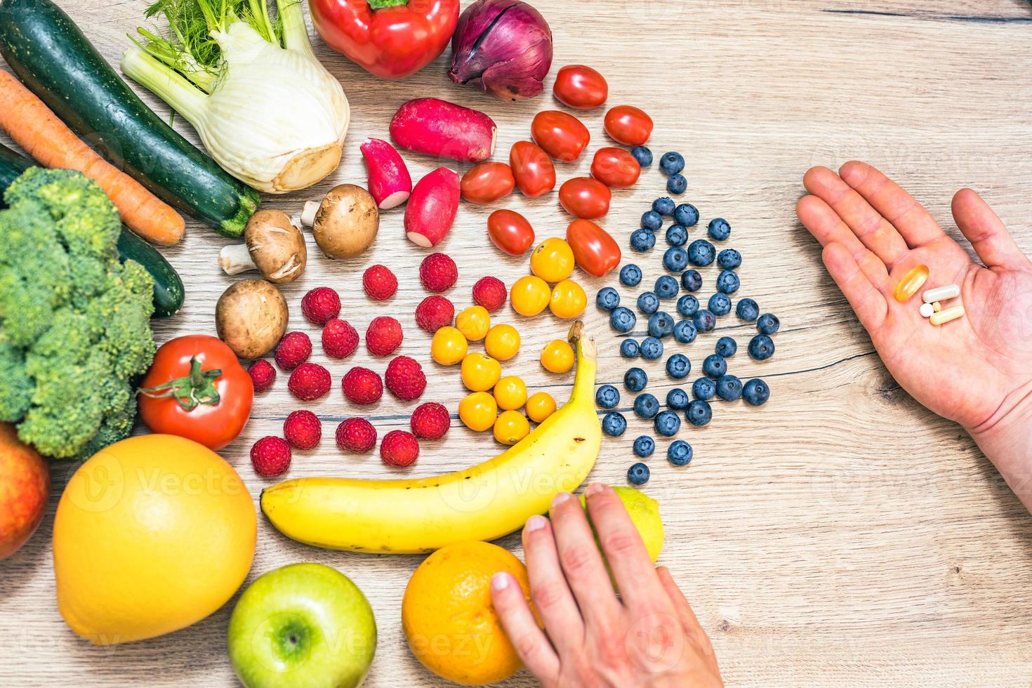 mano sujetando suplementos alimenticios sobre verduras y frutas para un estilo de vida saludable foto