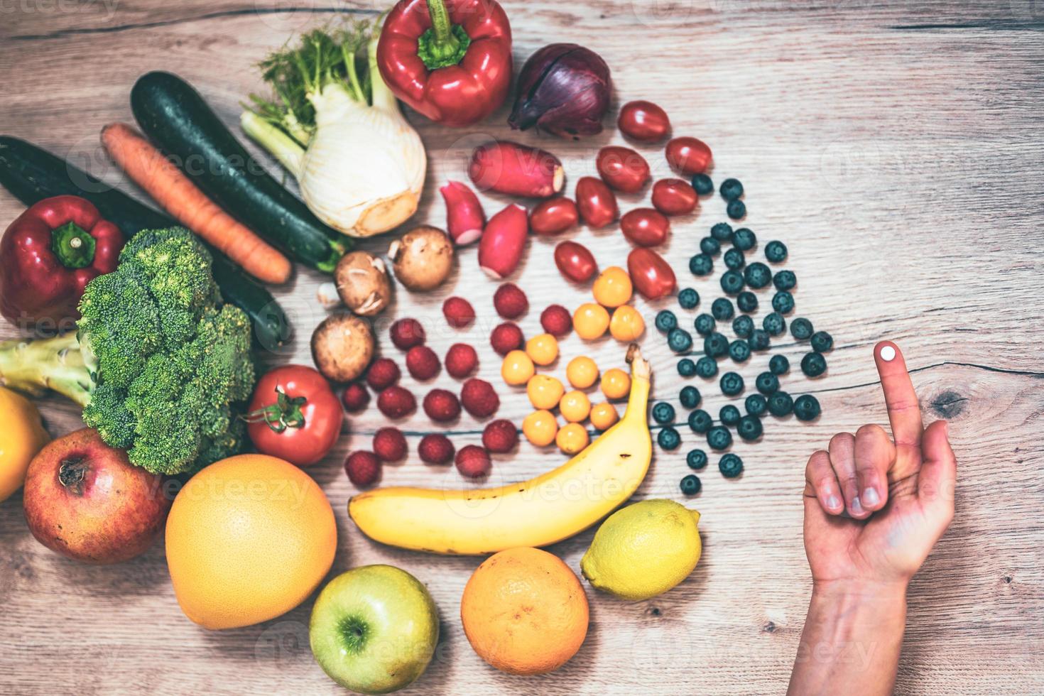 mano sujetando suplementos alimenticios sobre verduras y frutas para un estilo de vida saludable foto