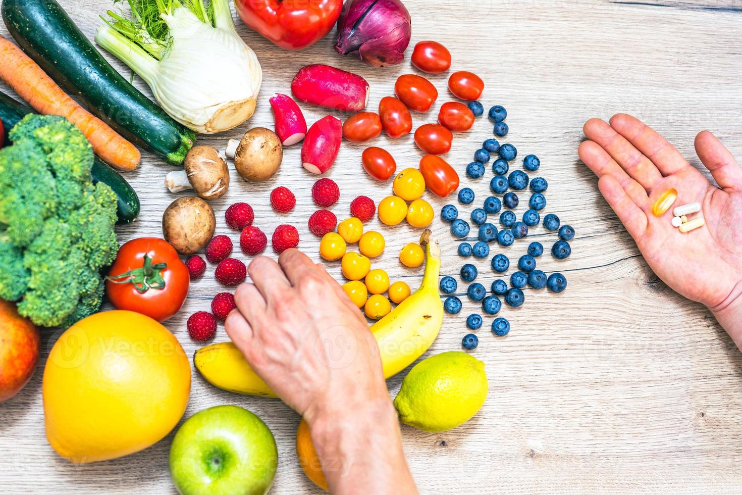 mano sujetando suplementos alimenticios sobre verduras y frutas para un estilo de vida saludable foto