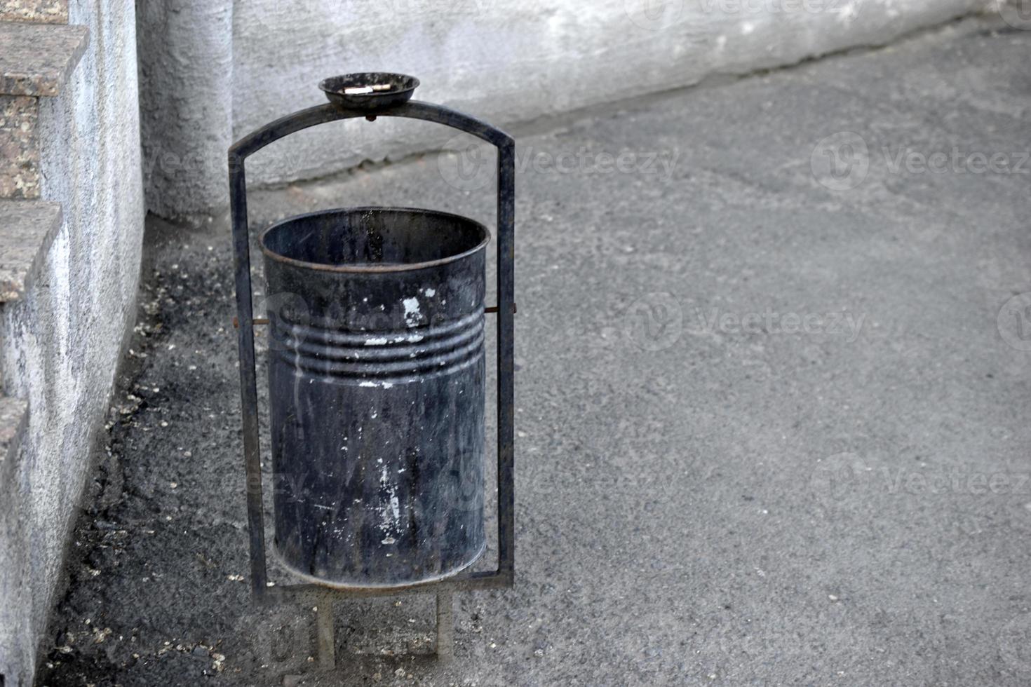 A trash can on the street with a place for cigarettes photo