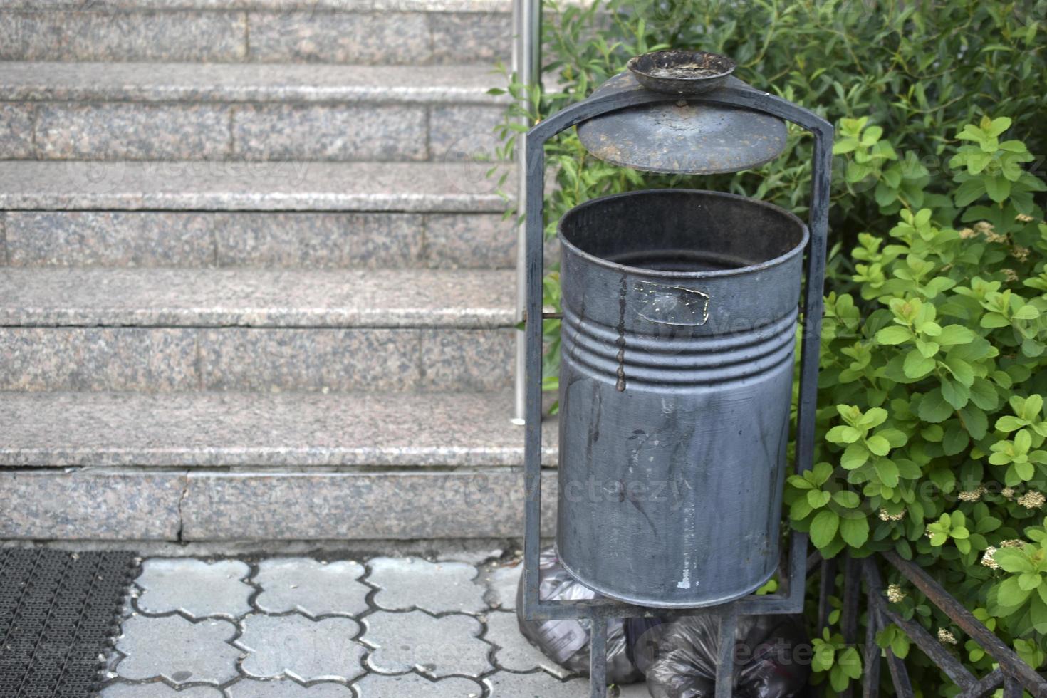 un bote de basura en la calle con un lugar para cigarrillos foto