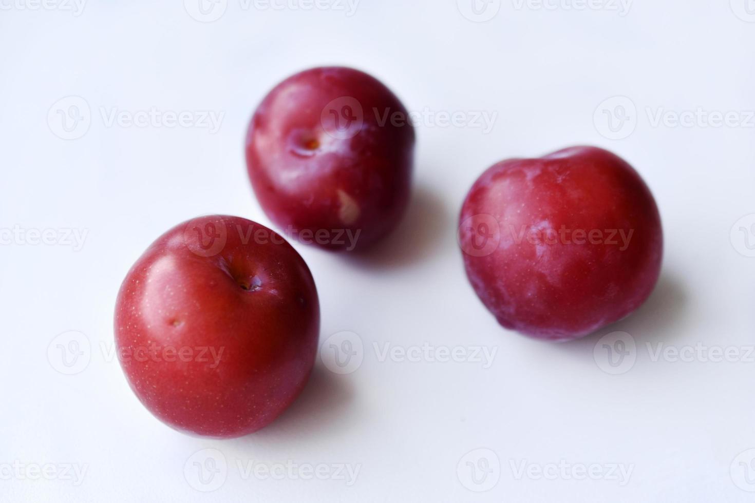 Juicy fresh red plums on a white background photo