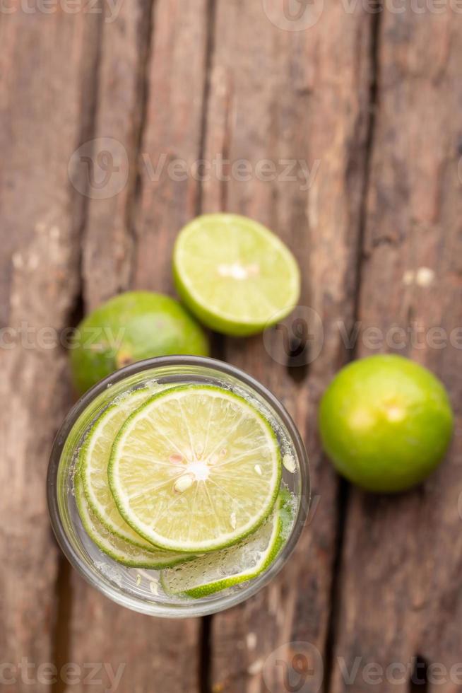 Top view green lime sliced in the soda water and glass place on the wooden table photo