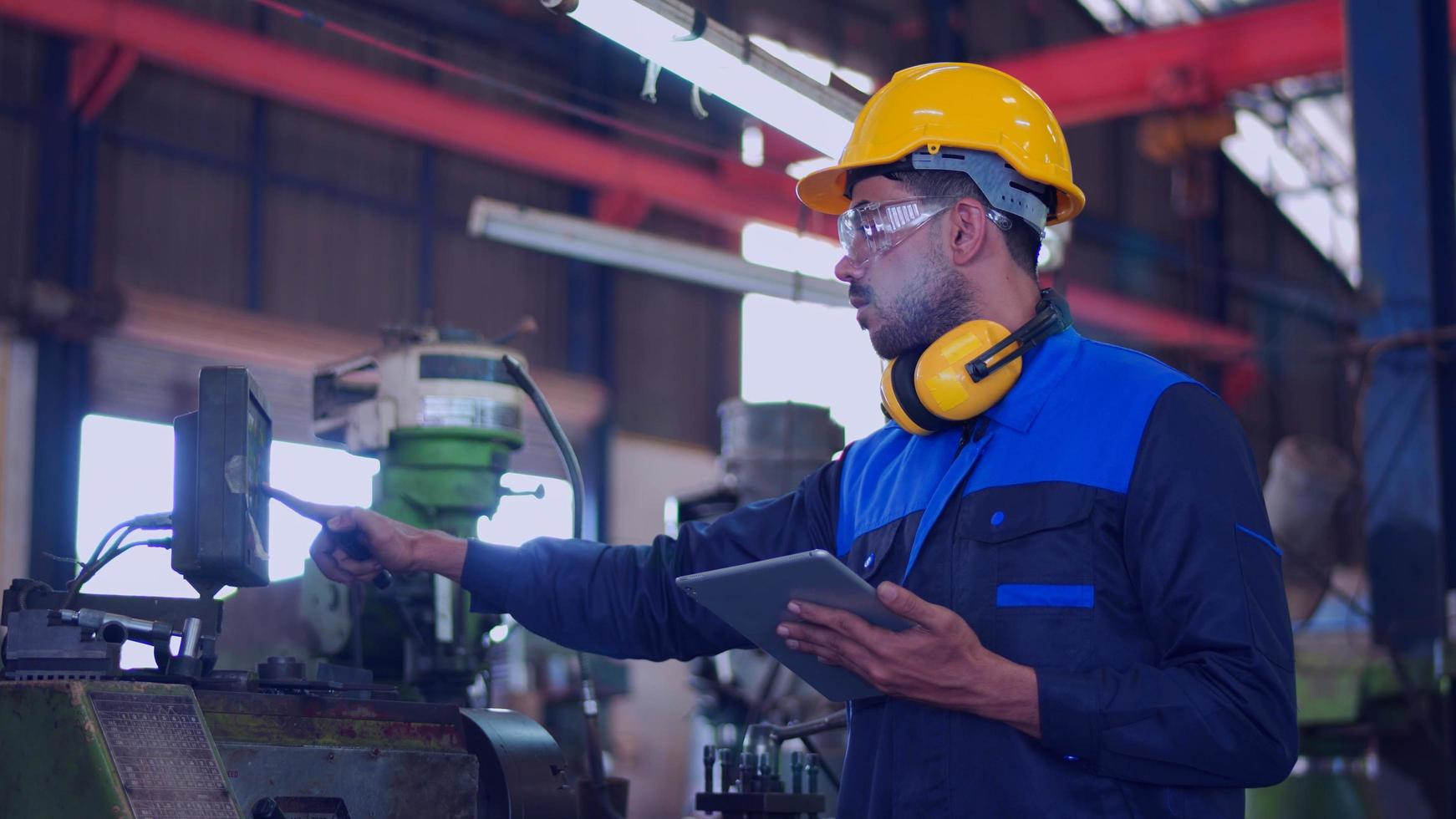 ingeniero de mantenimiento profesional, trabajador técnico, reparador con uniforme, casco de seguridad usando una máquina de control de verificación de computadora de tableta en fábrica. concepto de industria de maquinaria pesada de fabricación. foto