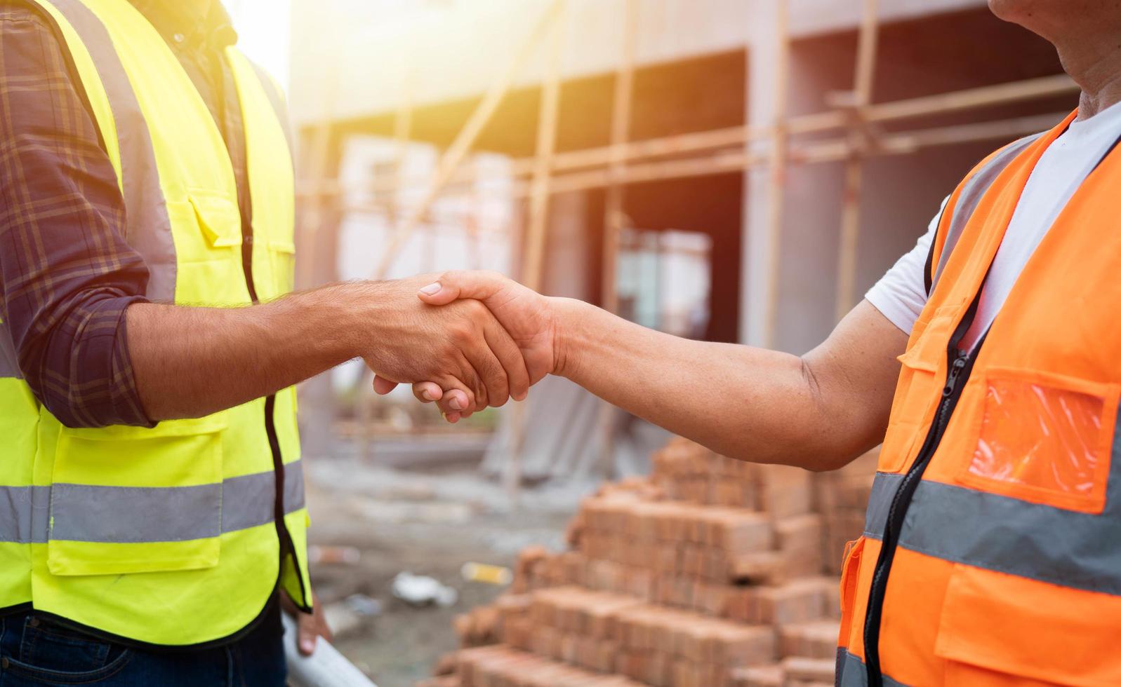 primer plano de apretón de manos, ingeniero civil profesional o arquitecto con contratista, trabajador capataz. éxito, mientras se encuentra con el proyecto de construcción y señala con un apretón de manos en el sitio de construcción. foto