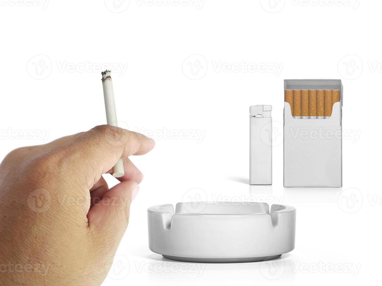 A cigarette in a hand, Cigarette pack, ashtray, and lighters isolated on white background photo