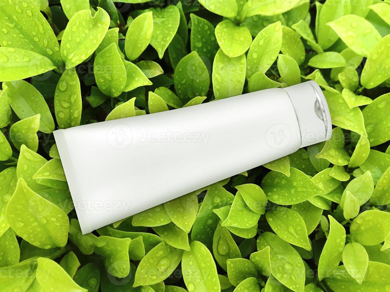 cosmetic plastic tube on green leaf background. top view photo