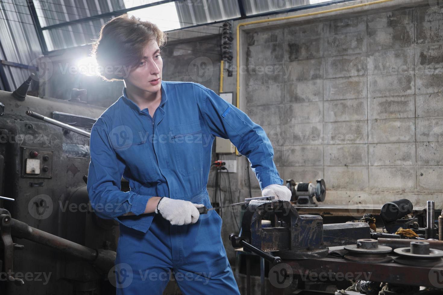 One professional young female industry engineer worker works in a safety uniform with metalwork precision tools, mechanical lathe machines, and spare parts workshop in the steel manufacturing factory. photo