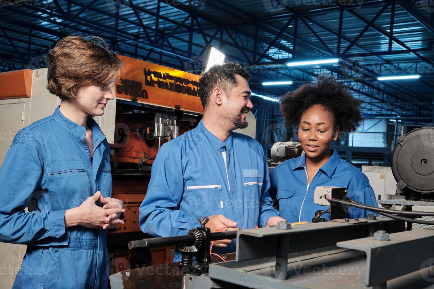 Multiracial professional industry engineer teams in safety uniforms work by inspecting machines' voltage current, checking, and maintaining at manufacture factory, electric system service occupations. photo
