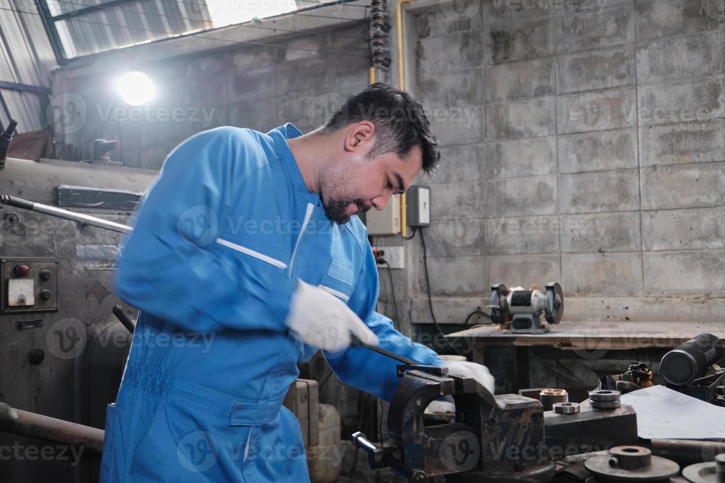 One professional Asian male industry engineer worker works in a safety uniform with metalwork precision tools, mechanical lathe machines, and spare parts workshop in the steel manufacturing factory. photo