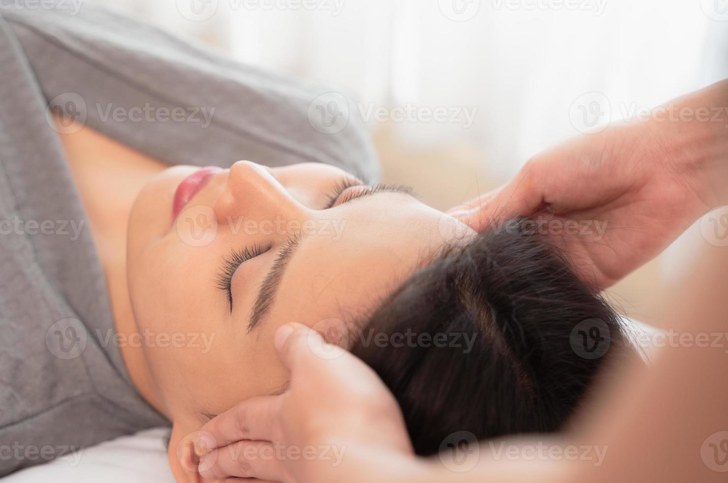 Young woman enjoying face massage in spa salon photo