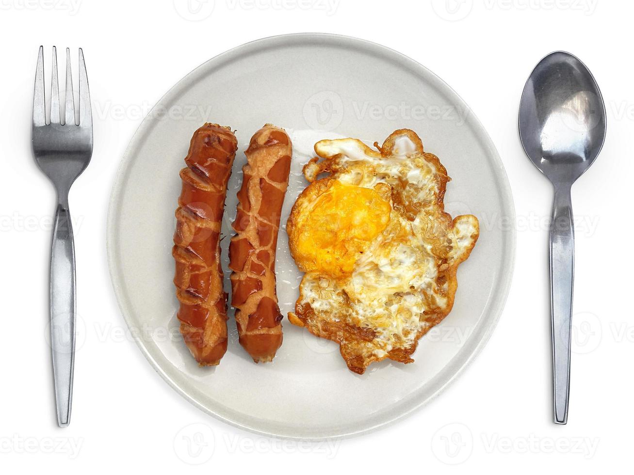 huevo frito en un plato con salchicha de cuchara y tenedor sobre un fondo blanco foto