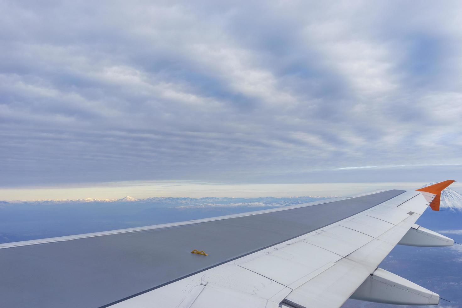 The wing of the aircraft against the background of the landscape with clouds photo