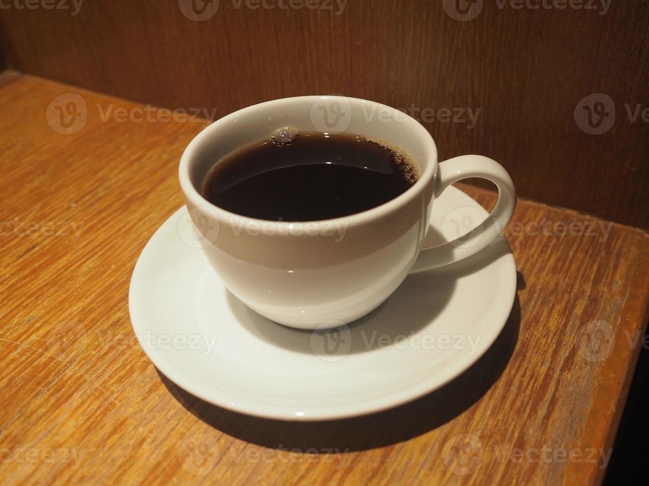 smoke on Black coffee in a white cup placed on a wooden table photo
