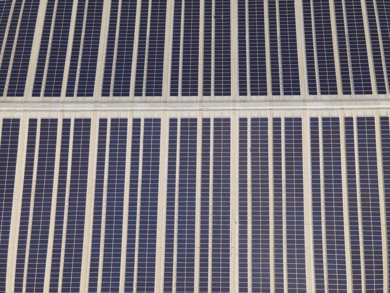 imagen aérea de drones de paneles solares instalados en el techo de un gran edificio industrial o almacén. edificios industriales.la energía renovable fuentes sostenibles energía verde fotovoltaica. foto