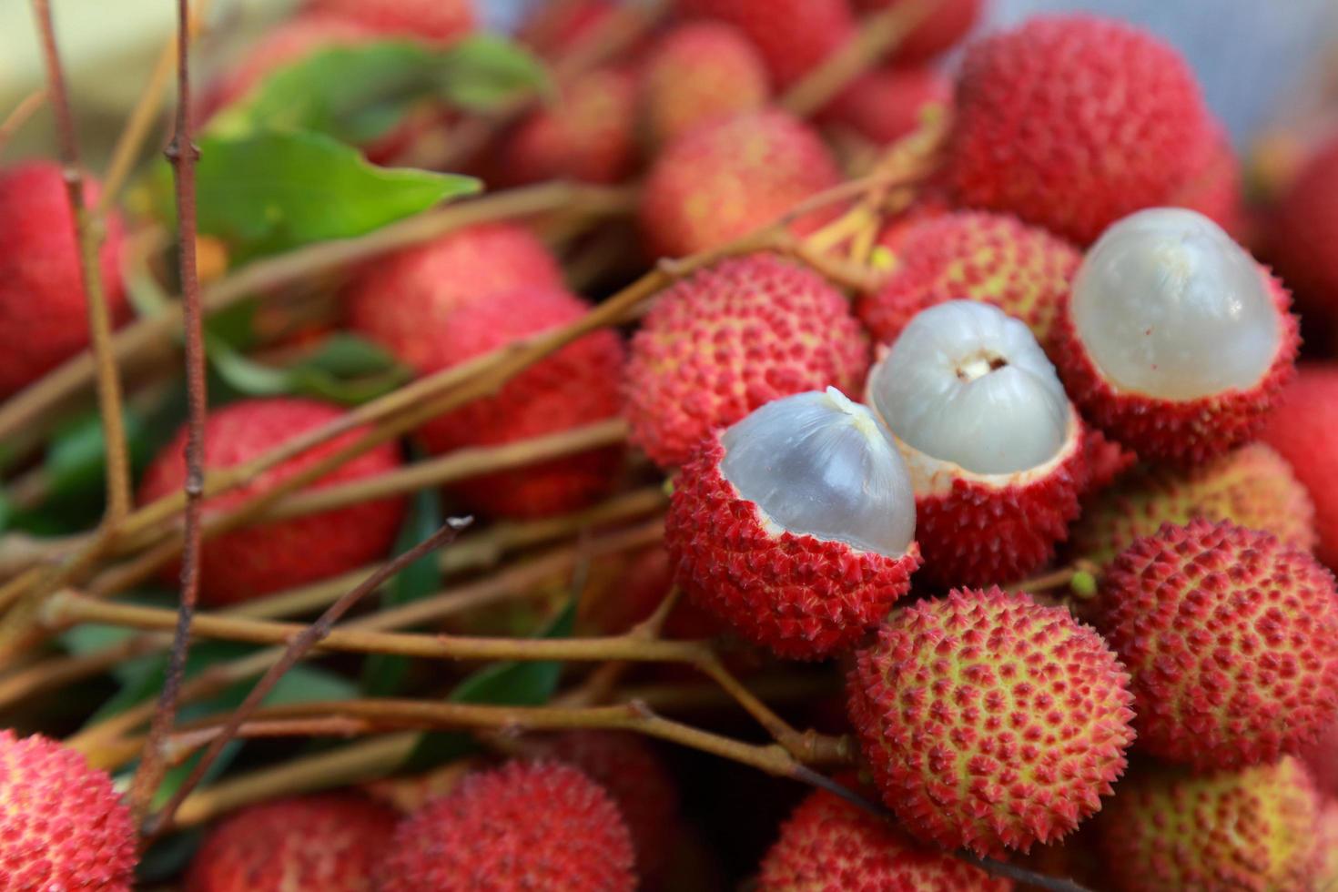 lichi, lichi fresco y pelado que muestra la piel roja y la pulpa blanca con hoja verde. foto