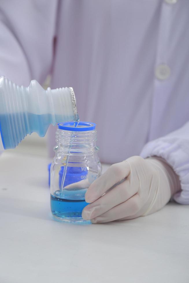 Woman scientist biochemist at the workplace makes the analysis in the modern laboratory. She is holding a dropper and a test tube photo