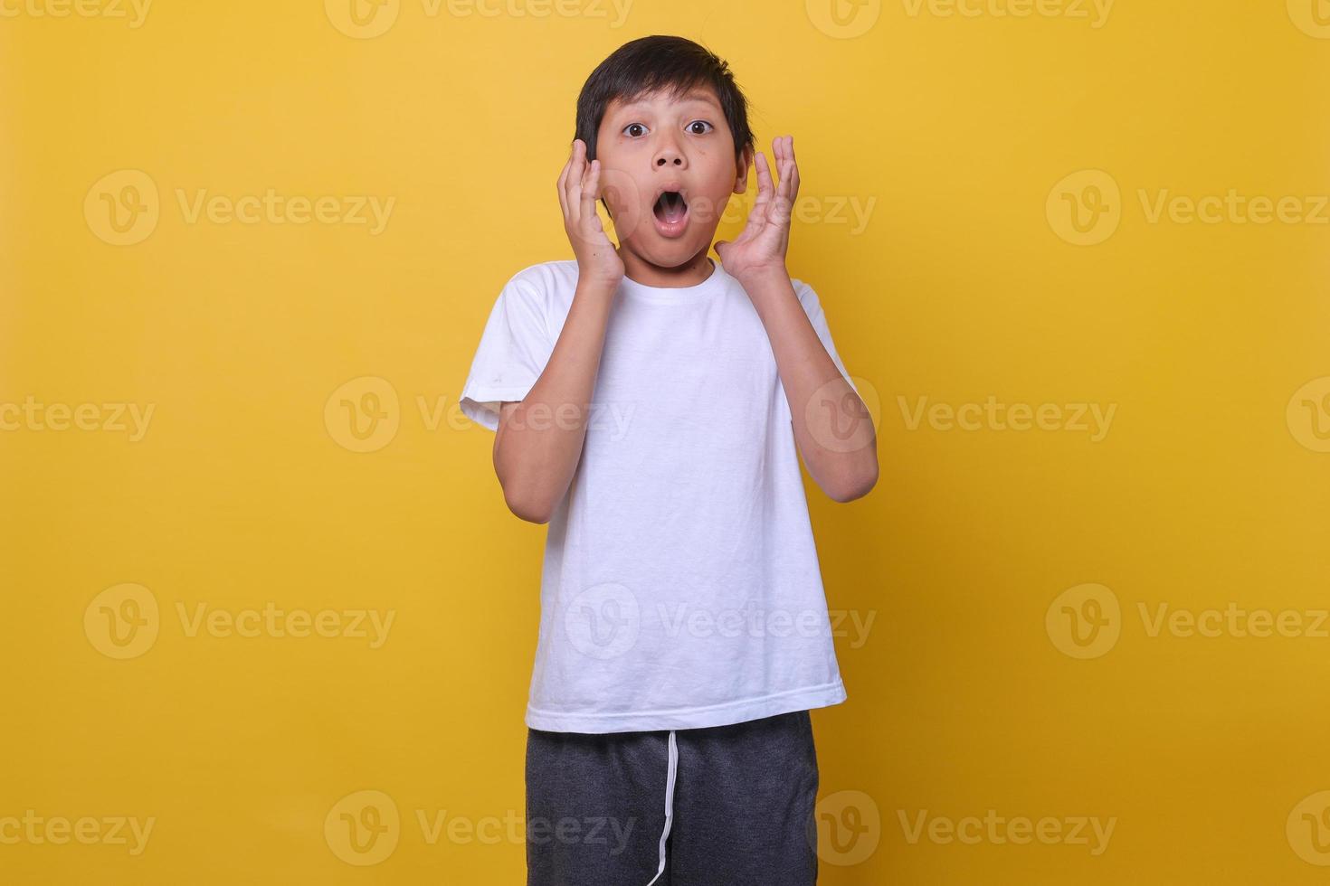 Asian boy in a casual style feeling suprised on yellow background. Mock up for kids fashion. photo