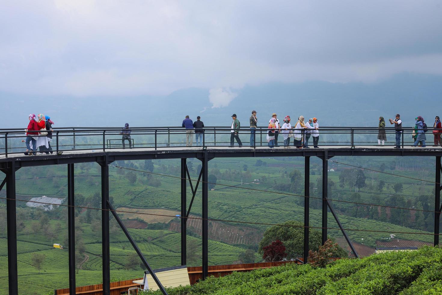 bandung, indonesia - 23 de mayo de 2022 grupo de turistas en el puente del cielo de nimo highland pangalengan bandung, java occidental, indonesia. vista de la plantación de té, la montaña y el lago. foto