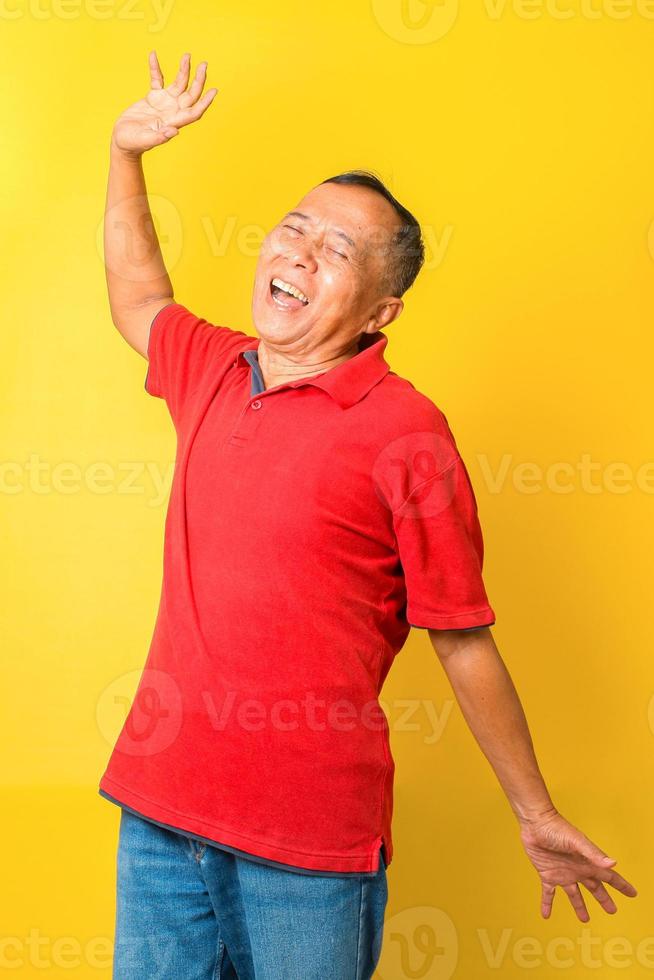 Asian senior man in casual style feel free stretching his hand and smiling isolated on yellow background. photo