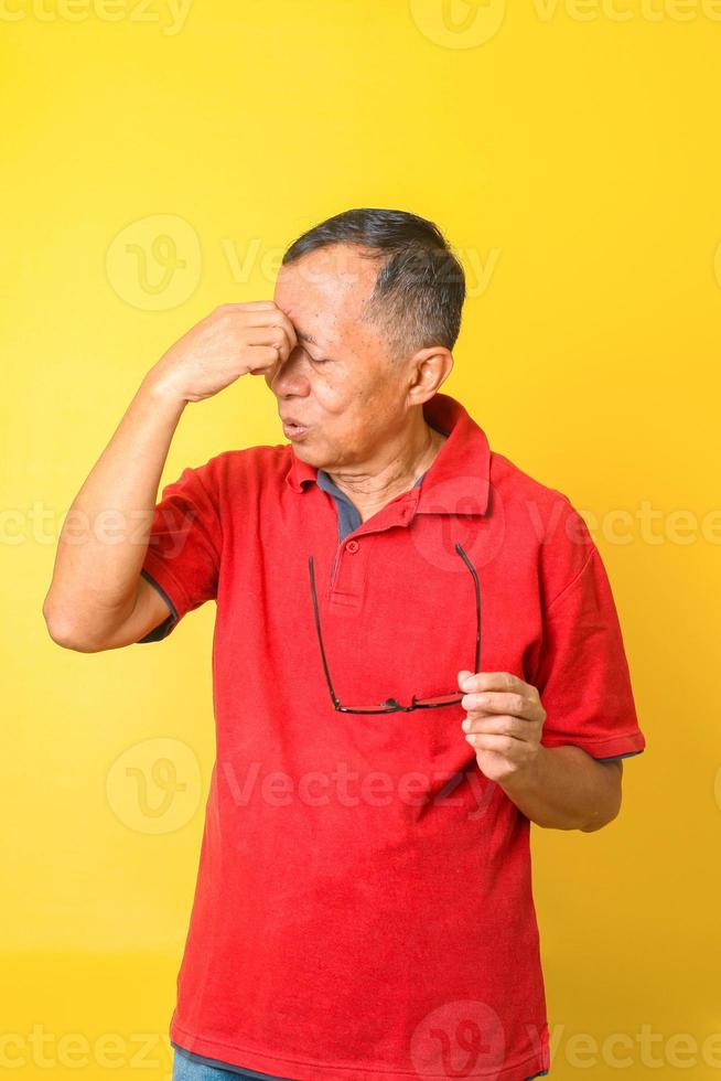 Asian senior man feels tired and dizzy after reading with eye glasses