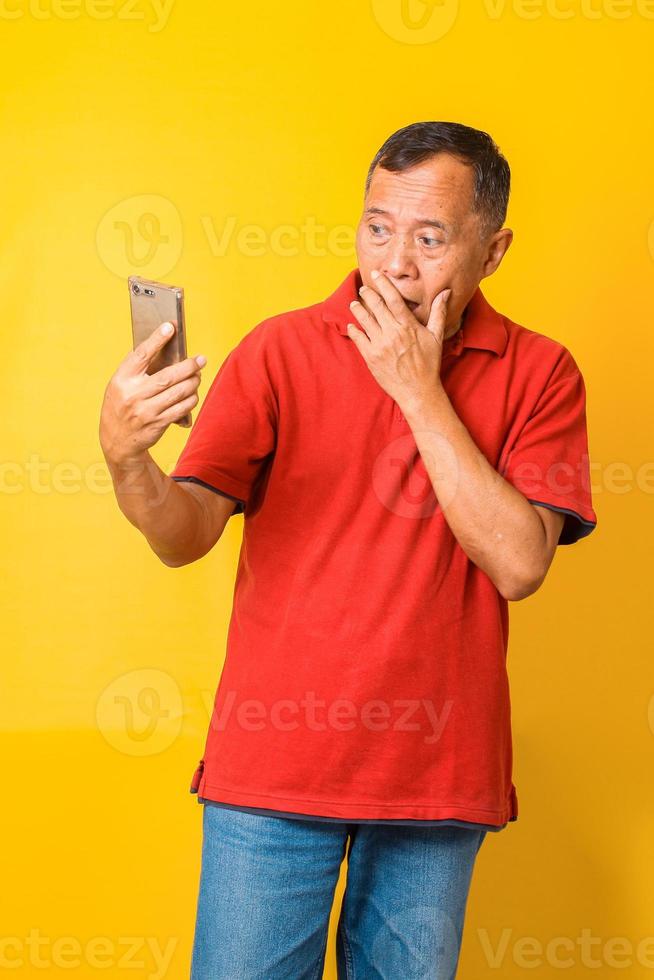 Portrait of surprised Asian senior man looking smart phone and being shocked. Human face expressions. Surprise, astonishment, wonder. photo