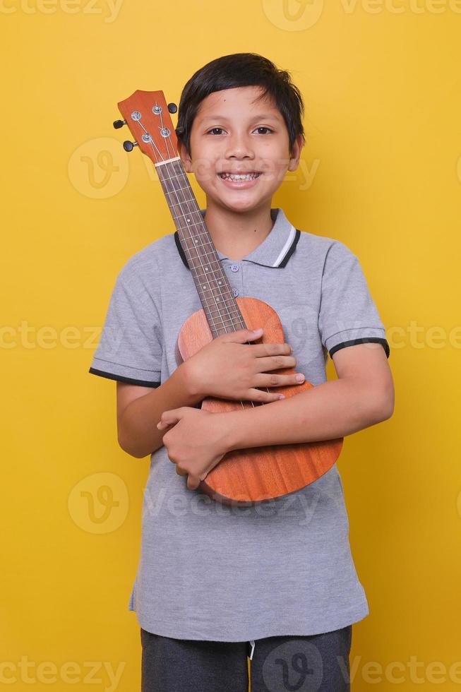 Happy asian boy is smile and holding ukulele.  Happy kid enjoying the music. Education, music school, lesson. Lifestyle and enjoying music. photo