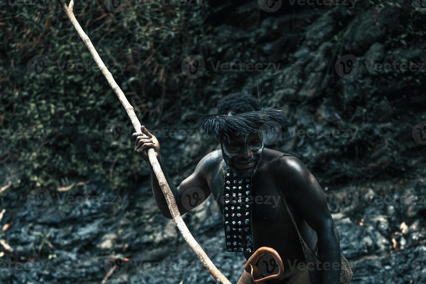 Potrait of Dani tribe man from Wamena Papua Indonesia wearing traditional clothes is spearing prey. photo