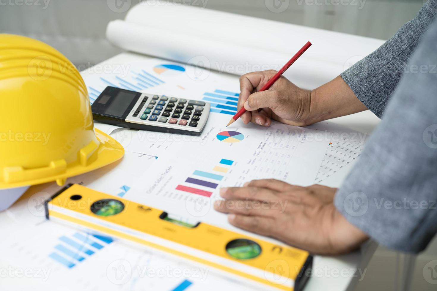 Asian engineer with architectural house plan project blueprint, graph and yellow helmet and engineering construction tools. photo