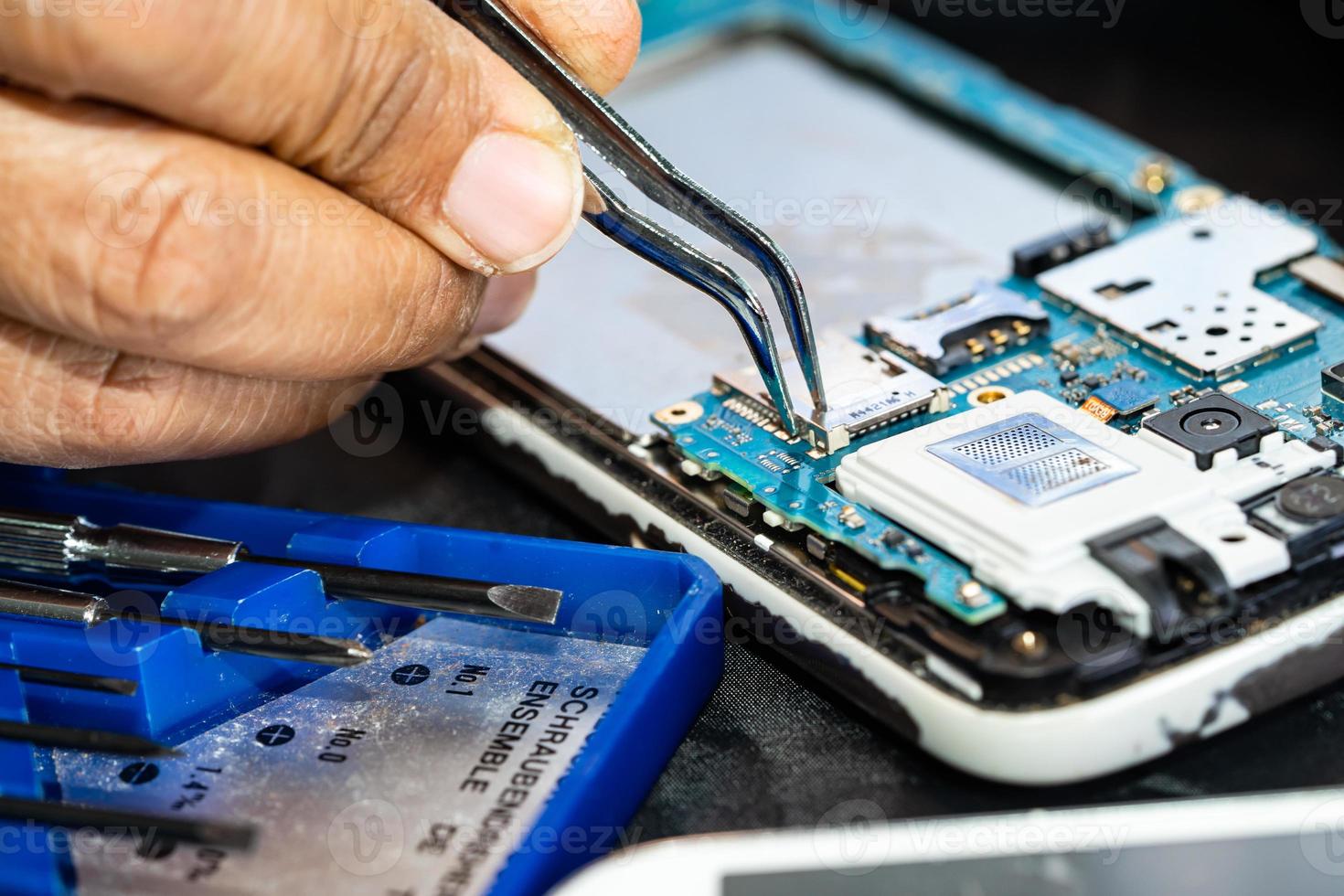 Technician repairing inside of mobile phone by soldering iron. Integrated Circuit. the concept of data, hardware, technology. photo