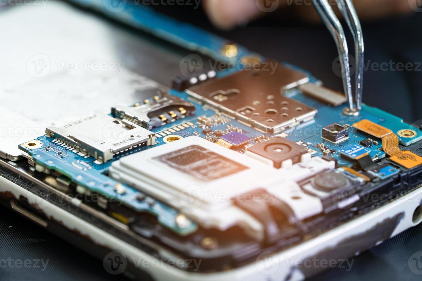 Technician repairing inside of mobile phone by soldering iron. Integrated Circuit. the concept of data, hardware, technology. photo