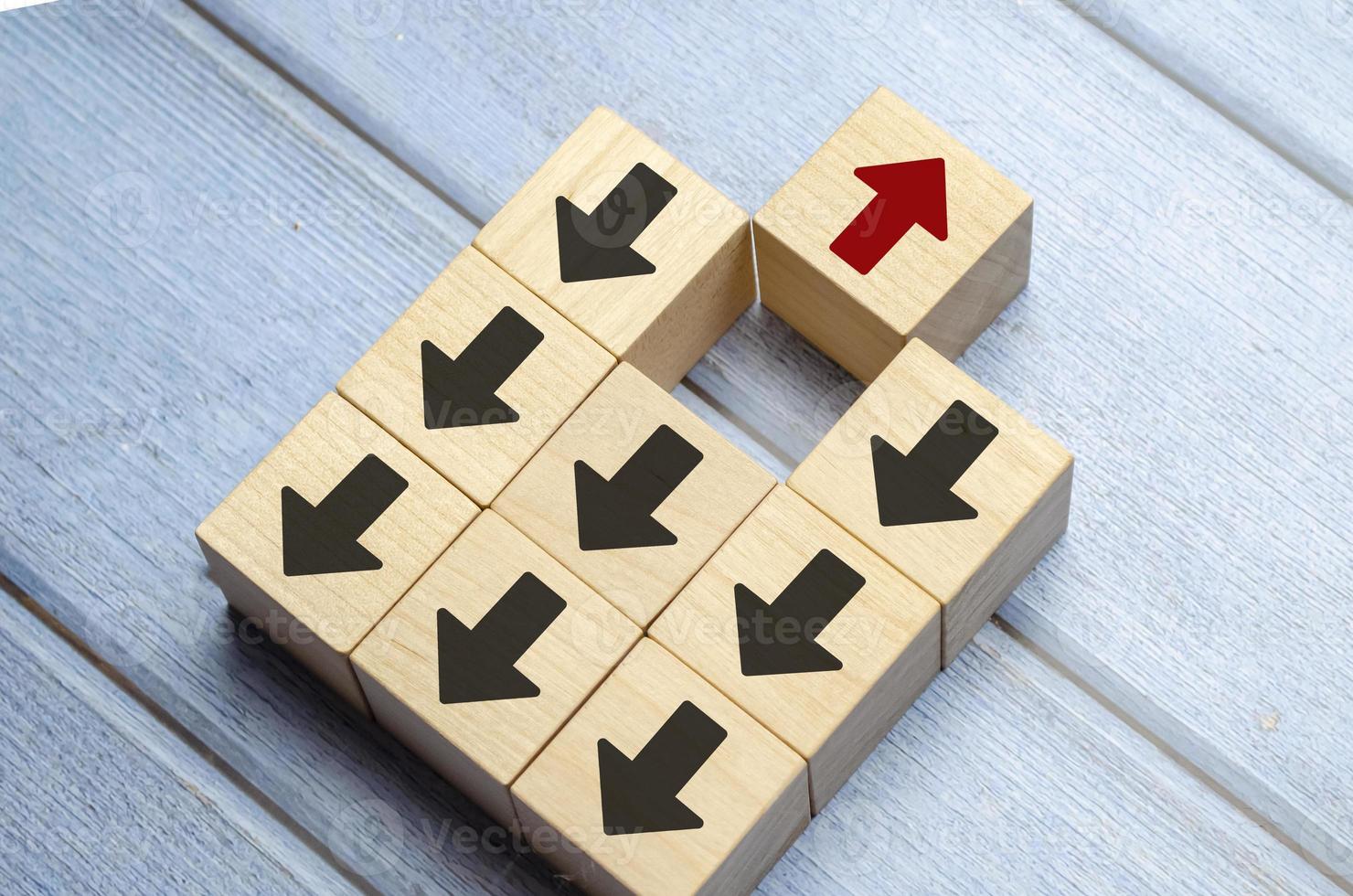 Wooden block with red arrow facing the opposite direction black arrows photo
