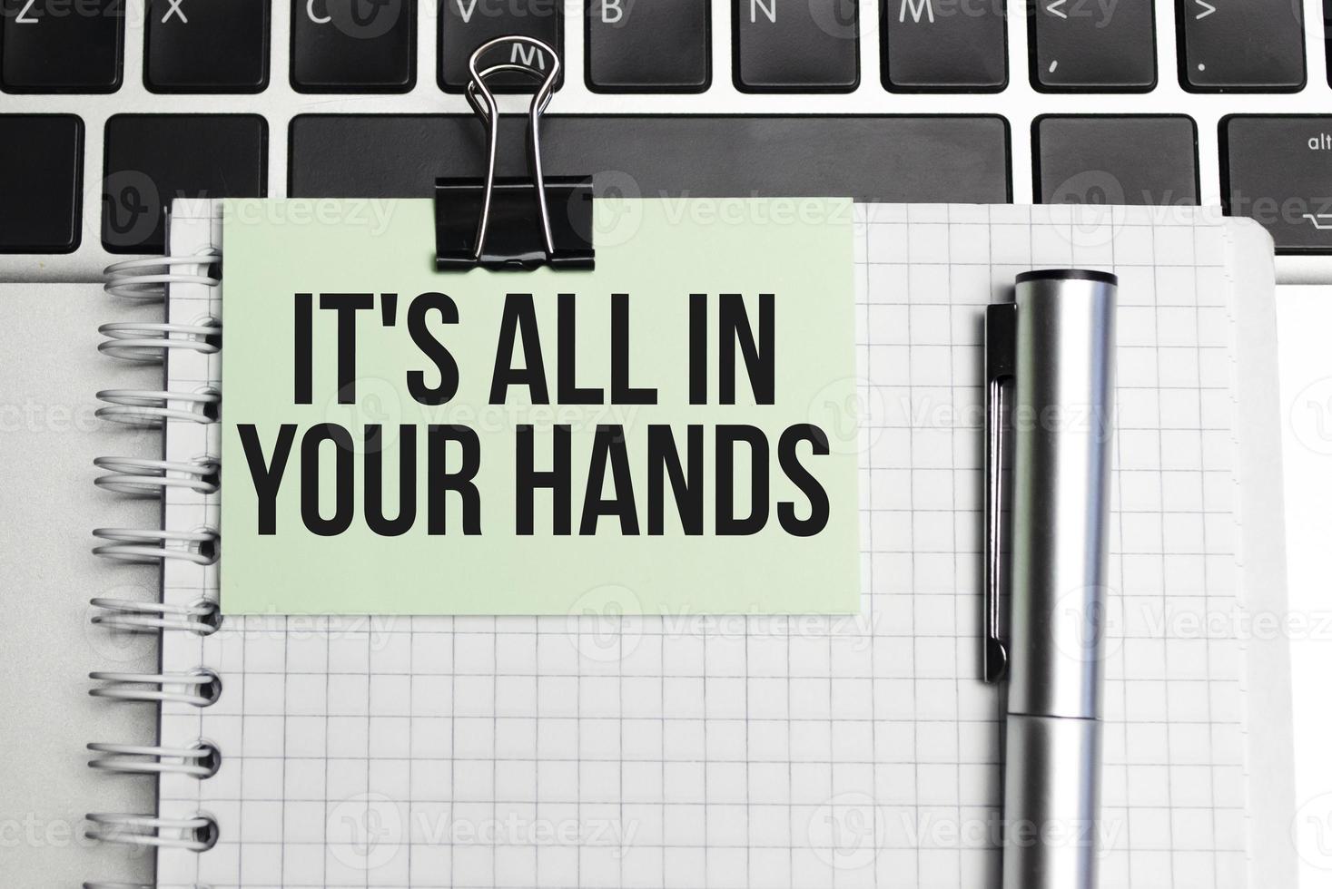 On the table laptop and notepad with text it's all in your hands photo