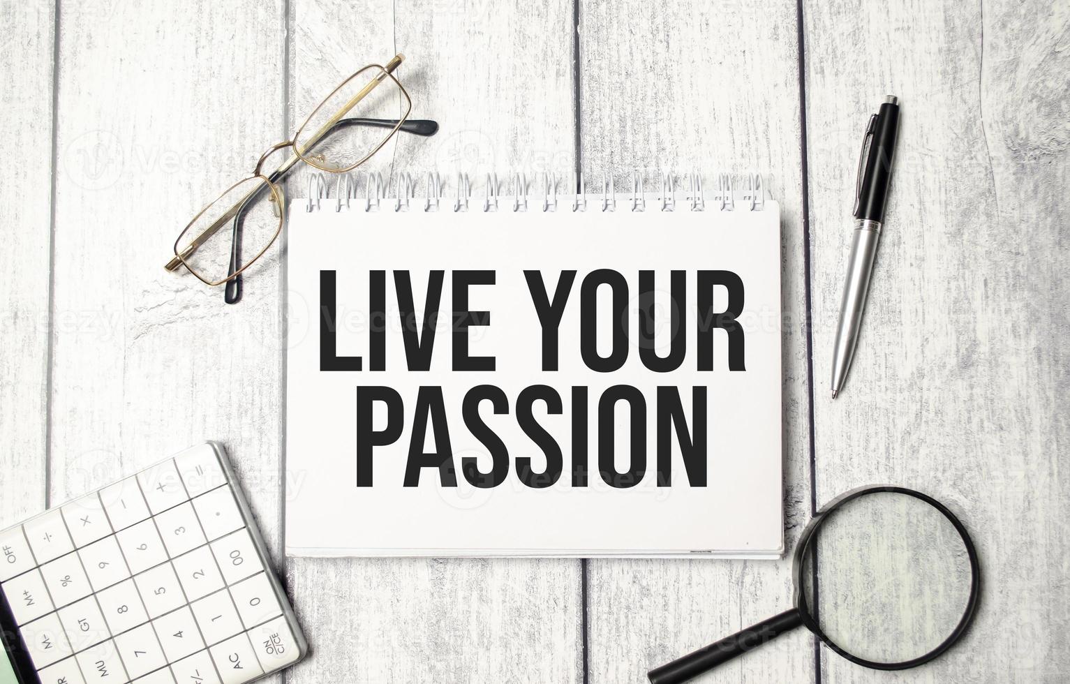 LIVE YOUR PASSION text on notepad with glasses, pen and calculator photo