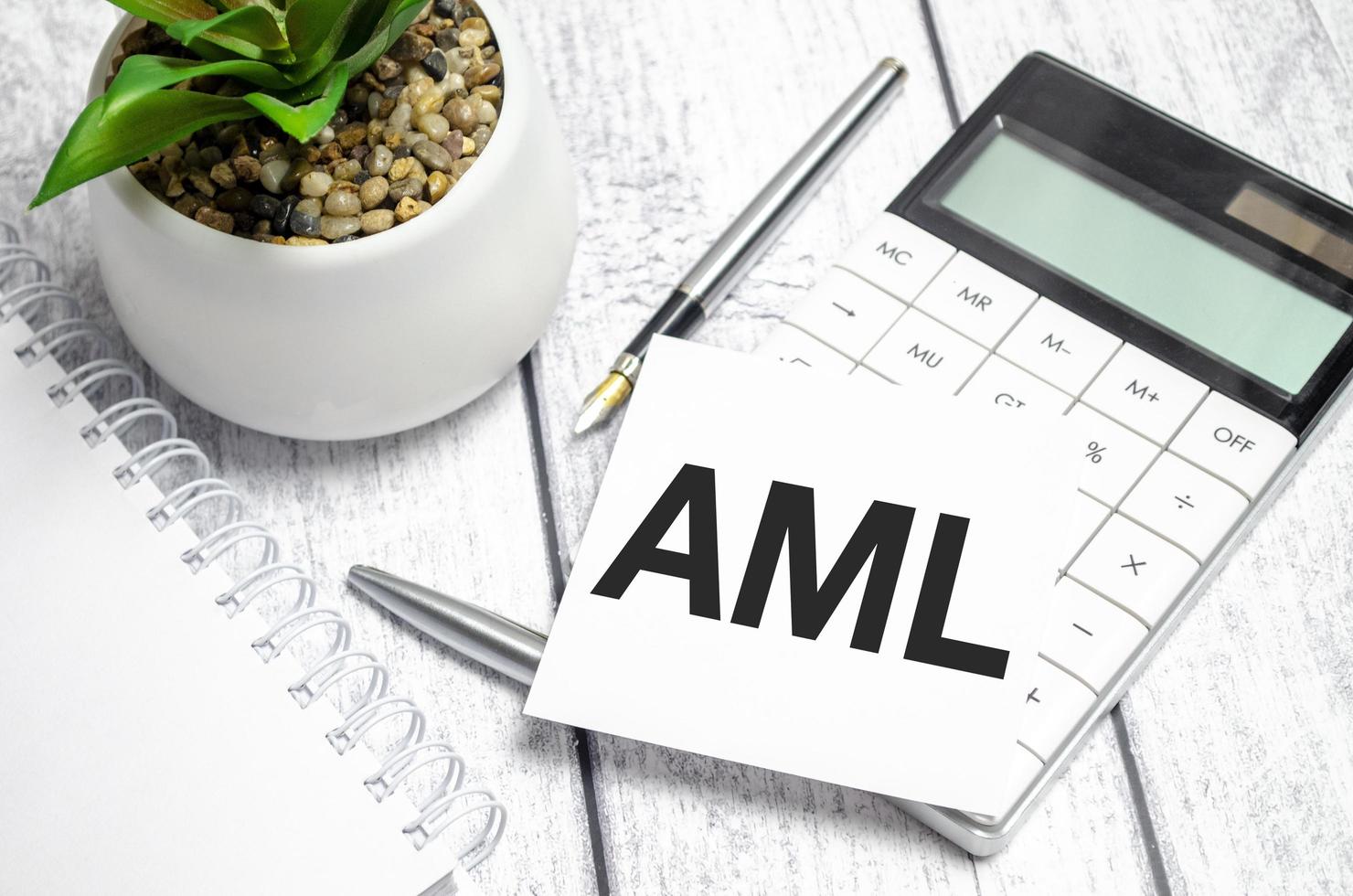 Text AML Anti-Money Laundering on paper card and calculator on wooden background photo