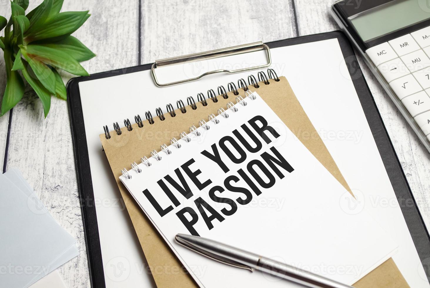 LIVE YOUR PASSION text on notepad and pen on wooden background photo