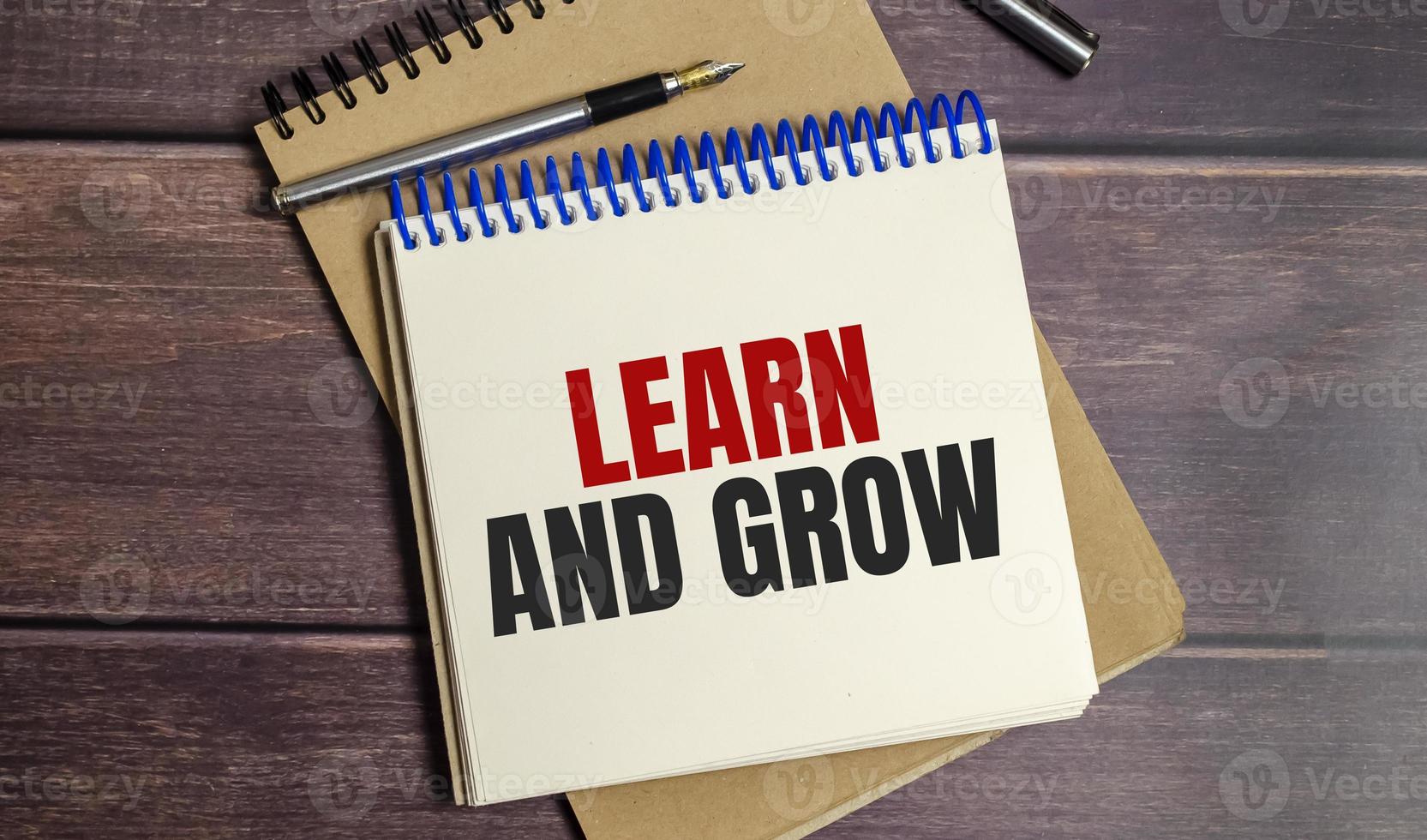 Learn and grow text on notepad and pen on wooden background photo