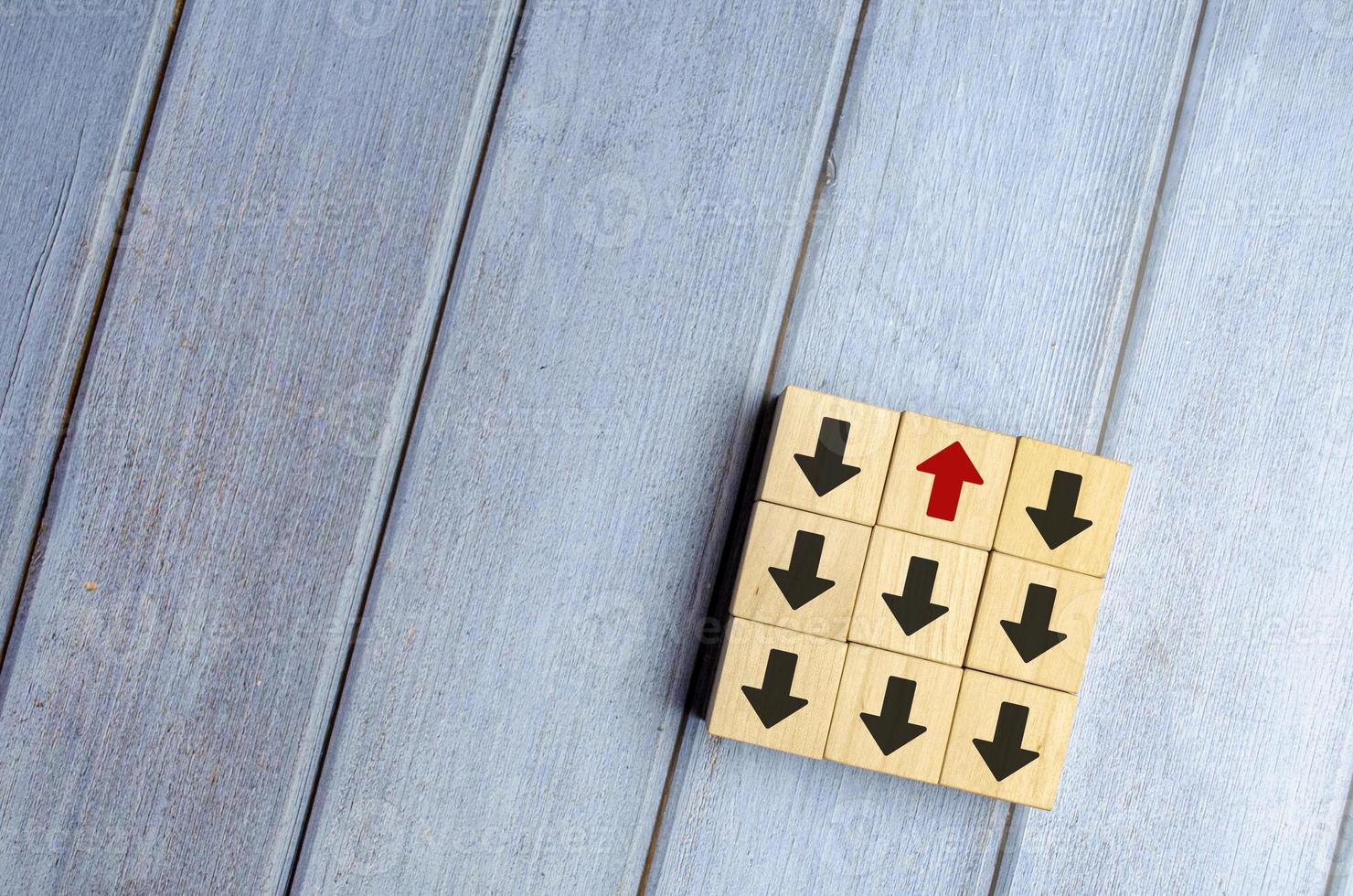 Wooden block with red arrow facing the opposite direction black arrows photo