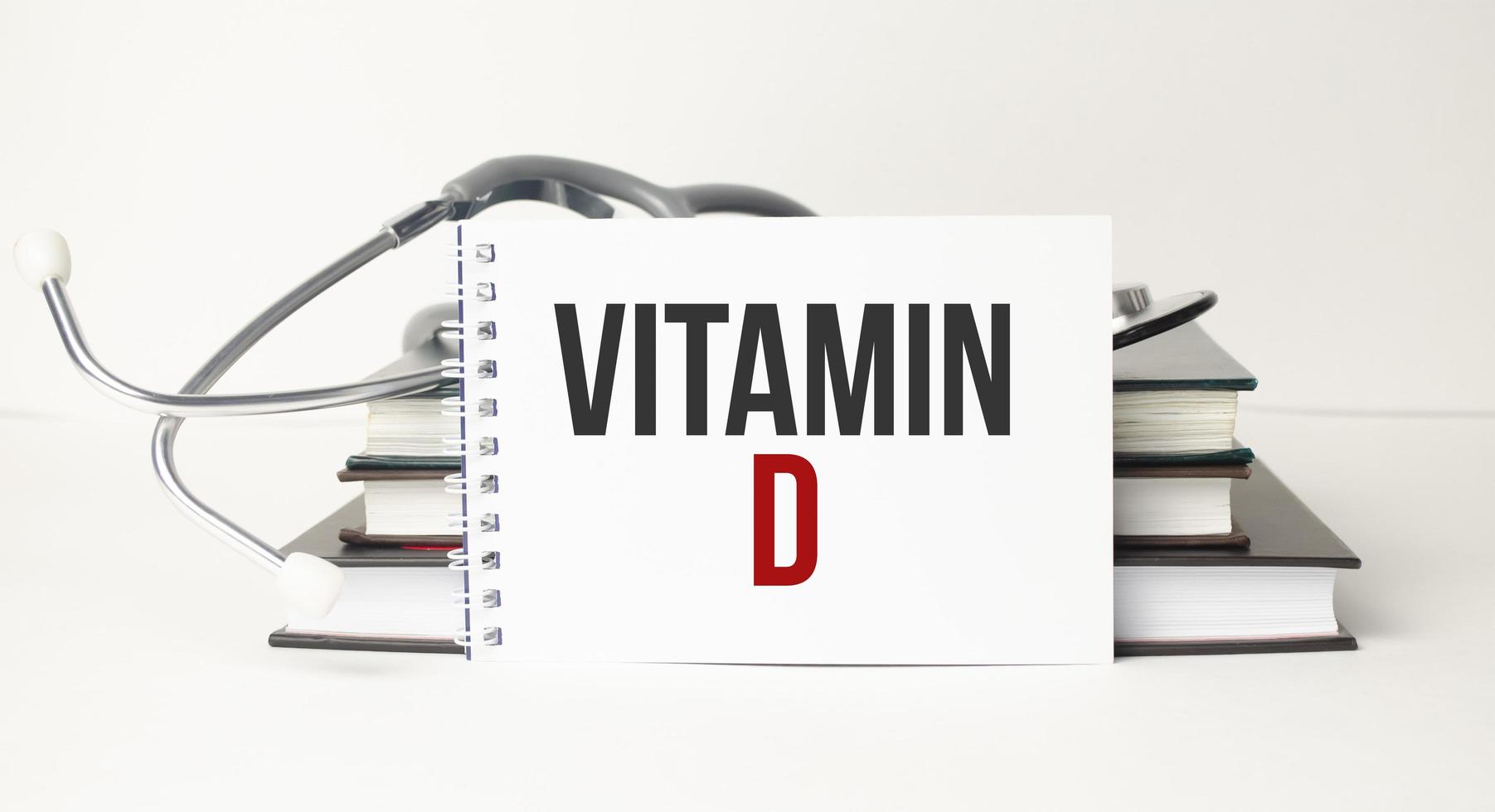 Text VITAMIN D on notebook with stethoscope and pen on wooden background photo