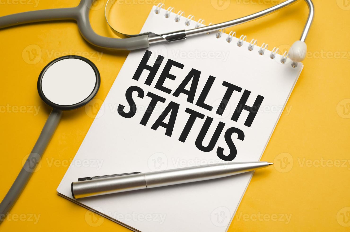 In the notebook is the text Health Status stethoscope, pills, and glasses photo
