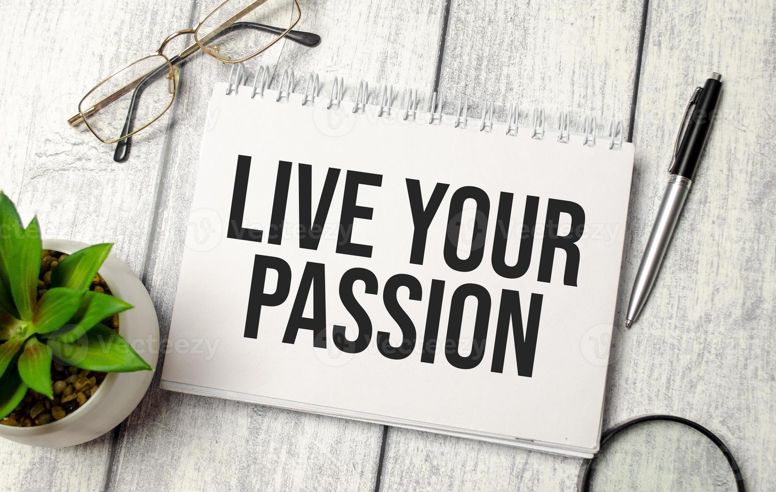 LIVE YOUR PASSION text on notepad with glasses, pen and calculator photo
