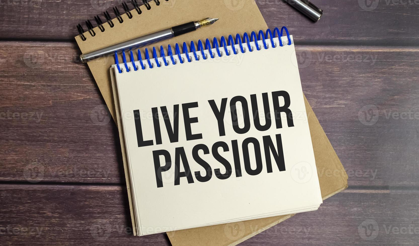LIVE YOUR PASSION text on notepad and pen on wooden background photo