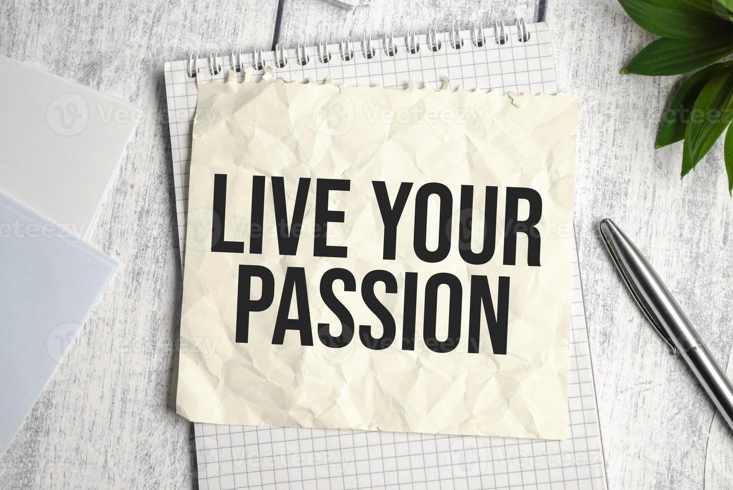 LIVE YOUR PASSION text on notepad and pen on wooden background photo