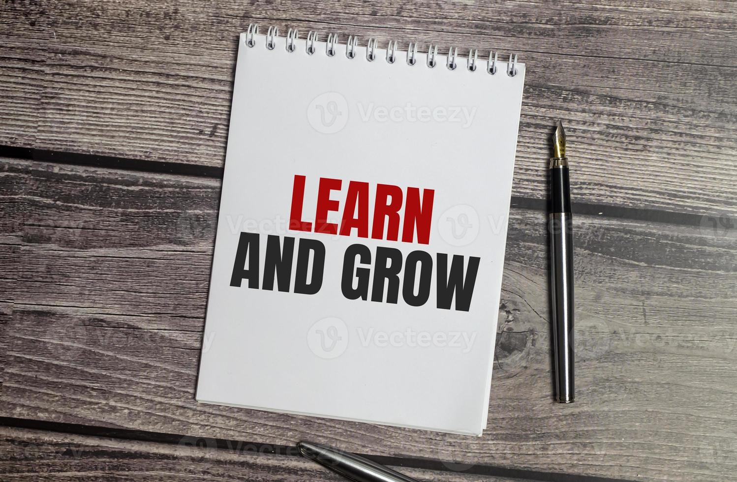 Learn and grow text on notepad and pen on wooden background photo